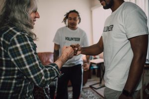 Three volunteers sharing a fist bump in a friendly indoor setting.