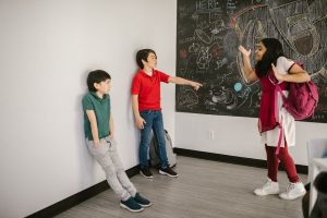 A diverse group of kids in a classroom with drawings on a chalkboard emphasizing anti-bullying.