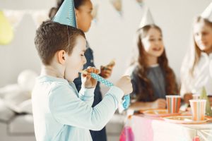 Kids having a fun and colorful birthday celebration indoors with party hats and decorations.