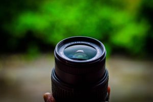 Detailed close-up shot of a Nikon camera lens against a lush green background.