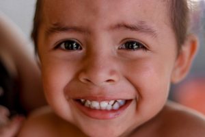 Close-up portrait of a smiling young child with bright eyes and a joyful expression.