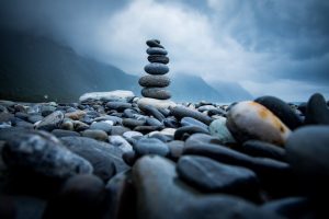 Serene beach scene with balanced rock tower and atmospheric sky.