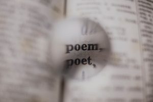 Close-up of words 'poem' and 'poet' magnified in a dictionary