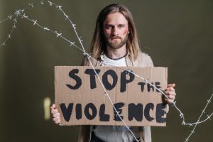 Man holding a 'Stop the Violence' sign with barbed wire emphasizing peace and protest.