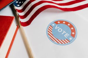 Patriotic image with American flag and vote symbol on paper.