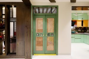 Stylish green doorway featuring intricate lattice designs, leading to a brightly lit modern kitchen.